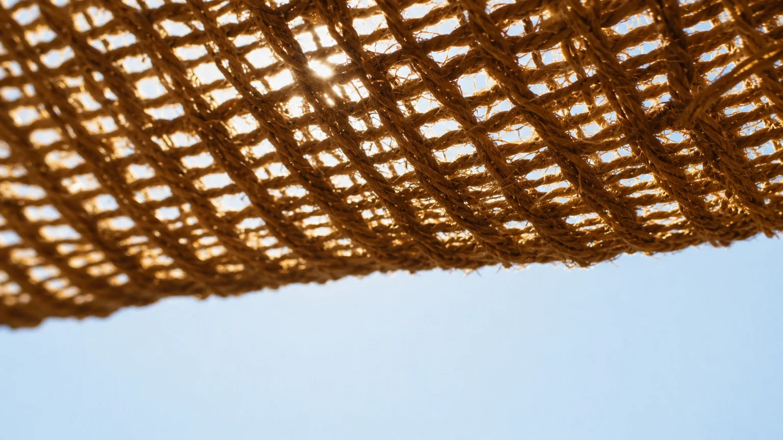Gros plan sur le tissage ouvert d'une toile en fibre de coco traversé par la lumière du soleil